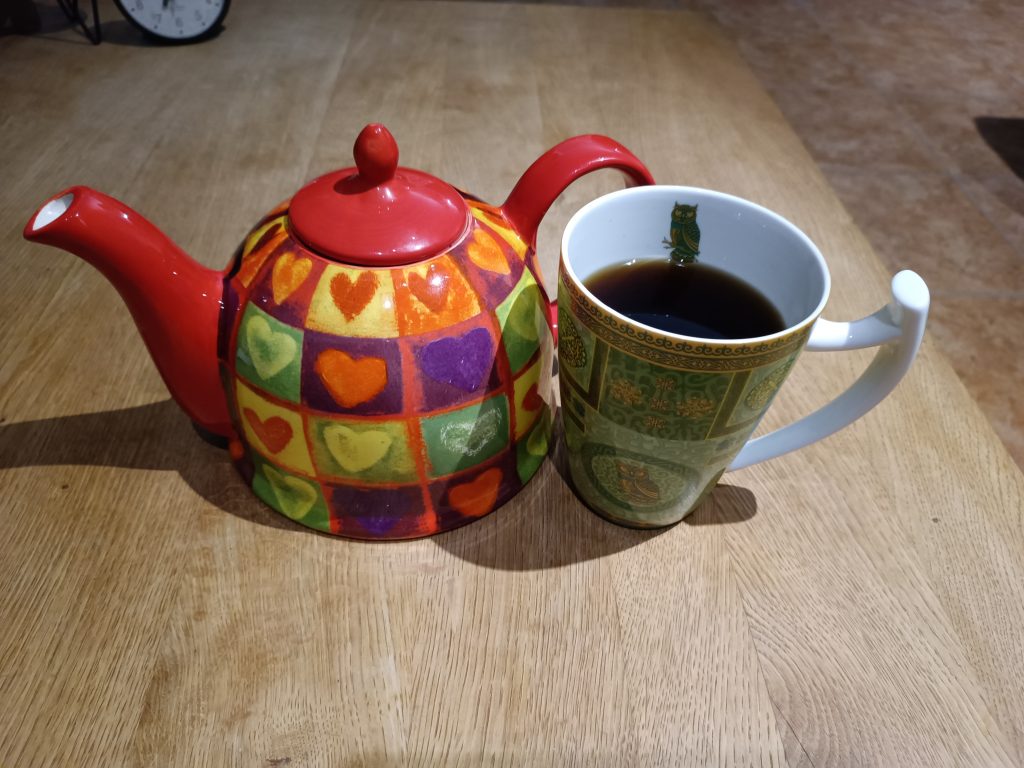 Eine rote Teekanne mit Herzen und eine Teetasse mit Uhu